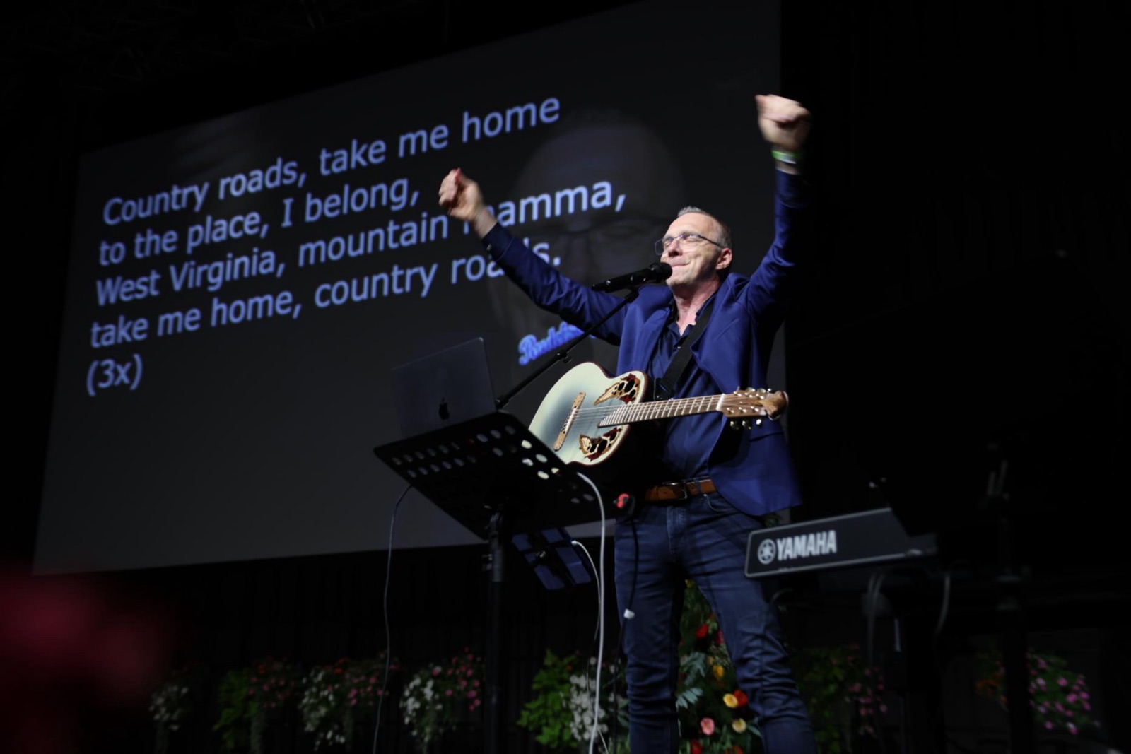 RUDELSINGEN beim Deutschen LandFrauentag 2026 - David Rauterberg mit Gitarre und erhobenen Armen vor der Songtext-Leinwand